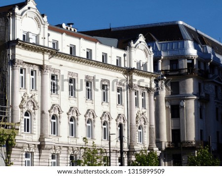 White stucco finished, richly decorated old European residential condominium building elevation detail in Budapest under blue sky and small trees on the street. Budapest has many famous landmarks. 