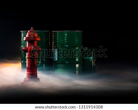 Red fire hydrant on a dark background with smoke. Red typical American fire hydrant on a background of green barrels and smoke