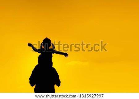 The family silhouette of the mother and child standing watch the sunset and the sky in orange in evening.