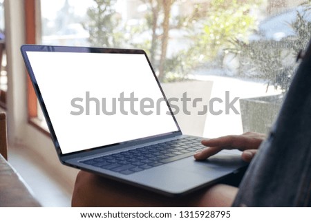 Closeup image of hand using and touching on mockup laptop touchpad while sitting indoors