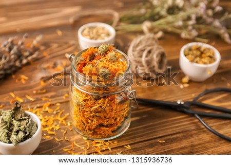 Glass jar with dried flowers on wooden table