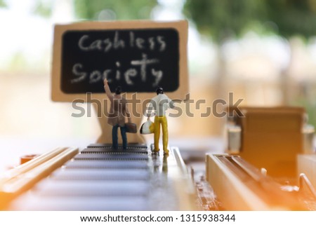 miniature mini  figures walking on Integrated Circuit straight to Cashless Society black board.Concept of cashless society for travel. Cradit card, Cash, hardware,  technology for new financial.