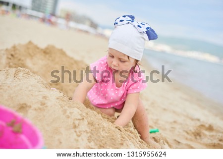 Cute baby girl at the beach near the sea in summer day