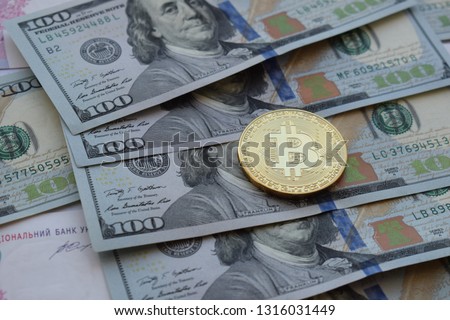 Golden Bitcoin on US dollars. Digital currency. Crypto currency top view. Real coins of bitcoin on banknotes of one hundred dollars. Exchange. Bussiness, commercial.