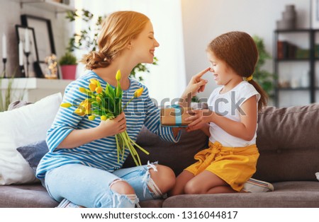 happy mother's day! child daughter congratulates mother and gives a bouquet of flowers to tulip and gift
