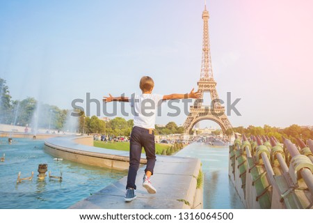 Happy cute boy running in centre of Paris. Background of Eiffel tower. Travel concept