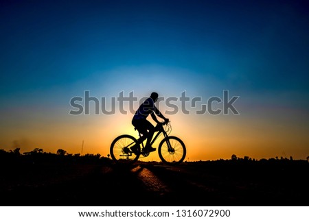 Silhouette of cyclist in sunset background.