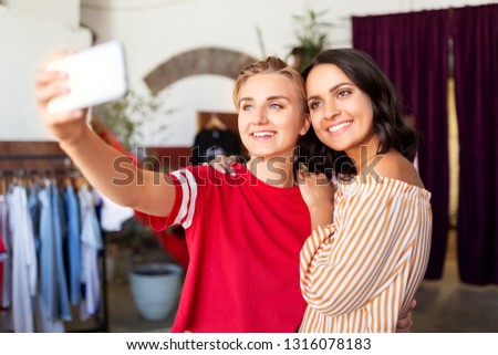 sale, shopping and technology concept - happy female friends taking selfie by smartphone at vintage clothing store