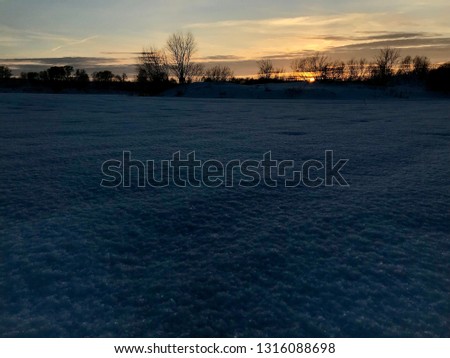 Sunset in the winter, scarlet sky over the snowy plain.