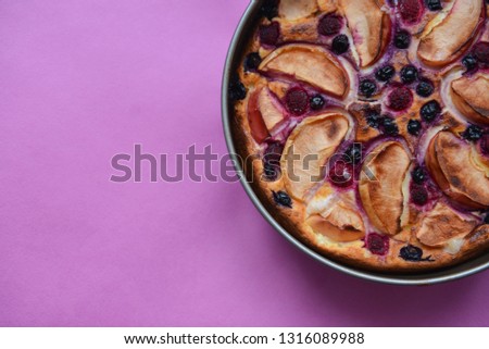 Delicious authentic hand-made homemade pie with apples and berries on a pink background texture. baking recipe to cook