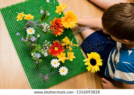 childhood meadow. kid playing with artificial flowers on artificial grass