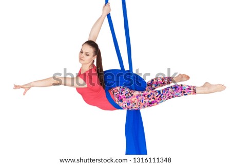 Young girl gymnast hanging on the canvases. Aerial gymnastics on a white background.