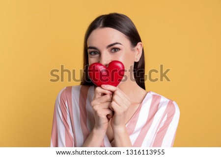 Portrait of young woman with decorative heart on color background