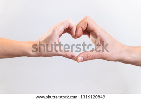 Man and woman make heart symbol on a white background. Love concept.