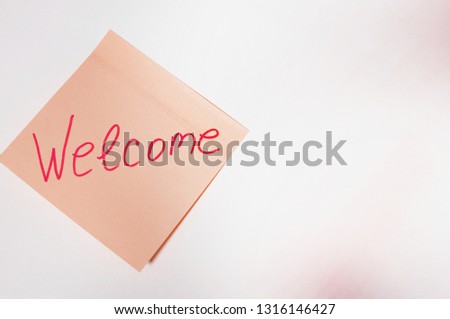 The sentence Welcome written by hand on a pink post it and put on the white table