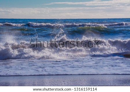 Stormy sea  with splashes from big waves. Large waves with white foam on the crest rise above the surface of the water and run to the shore. Background of beautiful nature