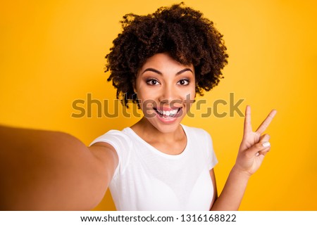 Close up photo beautiful amazing she her dark skin lady arm hand show v-sign make take selfies cute attractive white teeth wear casual white t-shirt isolated yellow bright vibrant vivid background