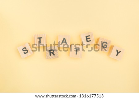 top view of strategy lettering made of wooden blocks on yellow background
