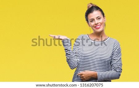 Young beautiful woman casual stripes sweater over isolated background smiling cheerful presenting and pointing with palm of hand looking at the camera.
