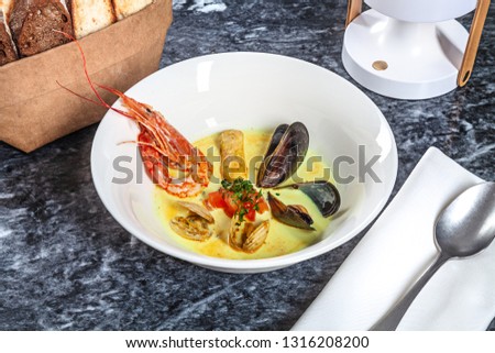 Close up view on served seafood cream-soup with bread. Soup with shrimp, mussels, scallops.  Restaurant food menu, recipe photo with copy space