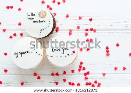 Delicious cupcakes with cute images for Valentine Day on white background. I love you to the moon and back. Romantic love background. Happy Valentines Day. Top view.