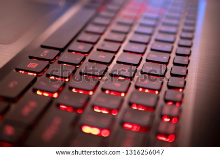 Black keyboard with red backlight, blurry close up 