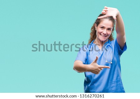 Young brunette doctor girl wearing nurse or surgeon uniform over isolated background smiling making frame with hands and fingers with happy face. Creativity and photography concept.