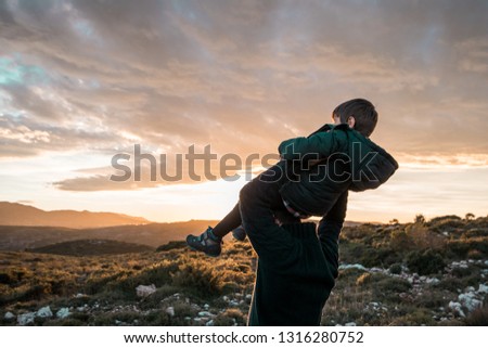 Father with his child on his shoulders at sunset. Concept of happiness and love between dad and son