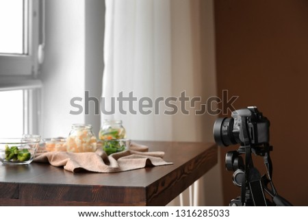 Professional photo camera near composition of food on table in studio