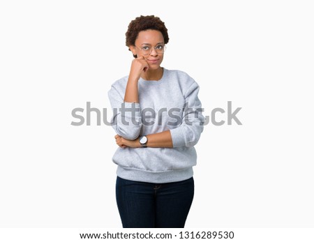 Young beautiful african american woman wearing glasses over isolated background looking confident at the camera with smile with crossed arms and hand raised on chin. Thinking positive.