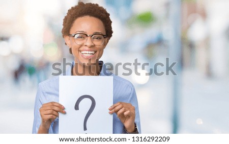 Young african american woman holding paper with question mark over isolated background with a happy face standing and smiling with a confident smile showing teeth