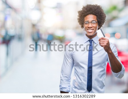 Afro american man holding credit card over isolated background with a happy face standing and smiling with a confident smile showing teeth