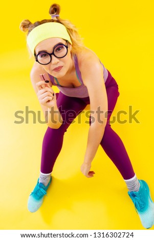 Woman in glasses. Top view of young woman wearing glasses and colorful clothes eating candy