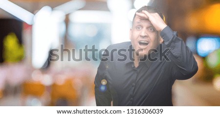 Handsome middle age arab business man over isolated background very happy and smiling looking far away with hand over head. Searching concept.