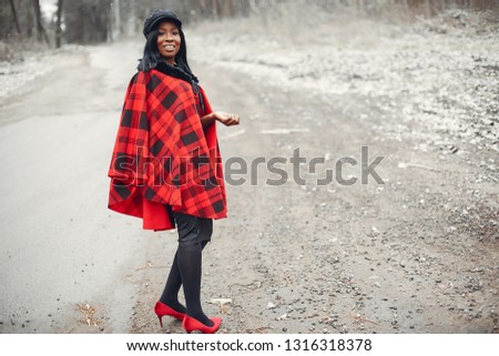Beautiful black girl in a red shirt. Ethnic woman in a winter forest