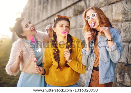 Grup of three girls with funny lips, glasses, stars, paper hearts on stick at the sunset having fun. Going crazy, smile at summer day. Hipster girls, colored dressed, with sunglasses and wrist watch.