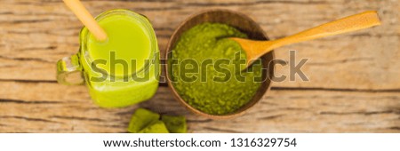 Green tea latte with ice in mason jar, matcha powder and candy made of matcha on wooden background. Homemade Iced Matcha Latte Tea with Milk zero waste BANNER, LONG FORMAT