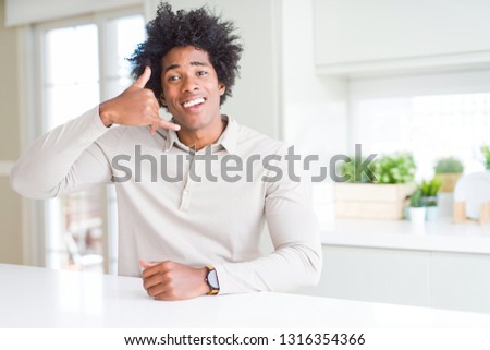 African American man at home smiling doing phone gesture with hand and fingers like talking on the telephone. Communicating concepts.