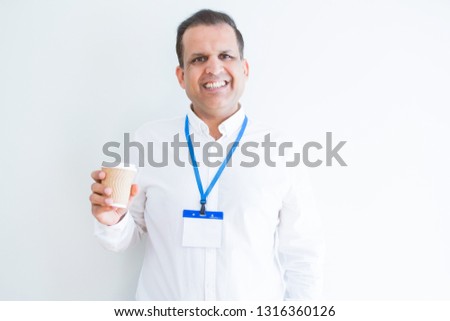 Middle age business man wearing ID card and drinking coffeeover white background with a happy face standing and smiling with a confident smile showing teeth