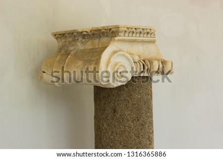 Greek antique column exhibit object on white wall background, museum sightseeing concept photography