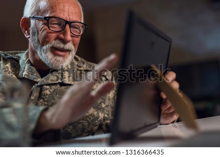 Nostalgic senior veteran recalling the memories and looking at picture in photo frame. 