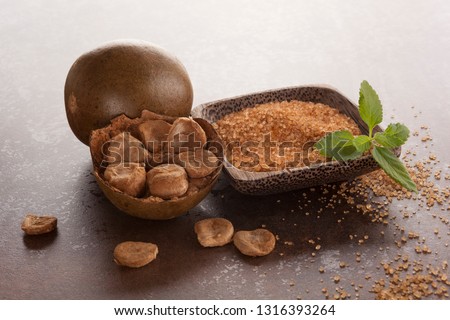 Luo Han Guo aka Monk fruit natural herbal remedy and sugar on brown background. Powerful healthy sweetener. Royalty-Free Stock Photo #1316393264