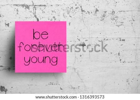 Sticky note on concrete wall, Be forever young