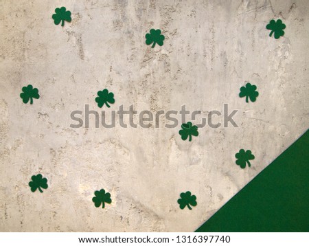 Green paper clover leaves on a gray concrete background. Saint Patrick's Day concept. Top view.