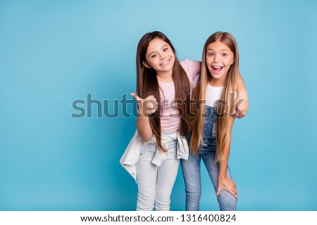 Portrait of two people nice cute lovely charming dreamy attractive cheerful straight-haired pre-teen girls siblings showing aside ad promotion copy space isolated on blue turquoise background