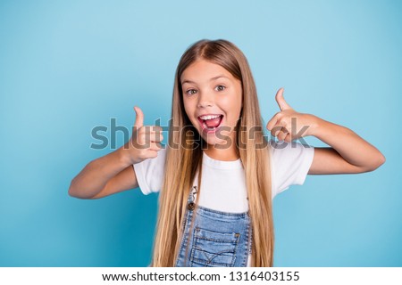 Close-up portrait of her she nice cute adorable lovely sweet attractive cheerful cheery straight-haired blonde pre-teen girl opened mouth showing thumbup isolated on blue pastel background Royalty-Free Stock Photo #1316403155