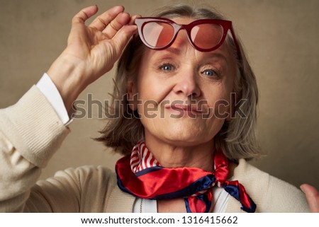 Cheerful pretty elderly woman wearing a red scarf around her neck with glasses