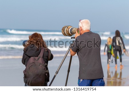 Group of photographers take photos with very large lenses at the sea.