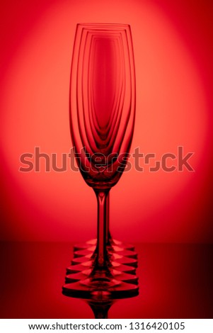 wine glasses standing one by one on a red gradient background
