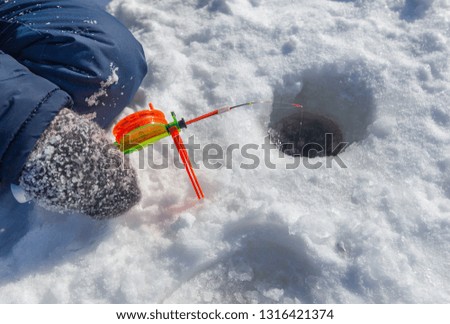 Boy fishing with a fishing rod on the ice in winter .